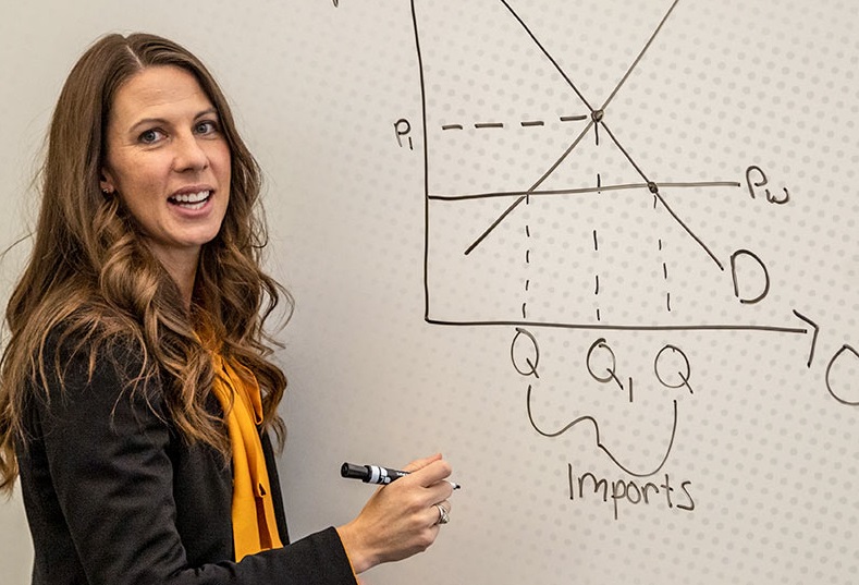 UA instructor in the undergraduate business program writes on a whiteboard.