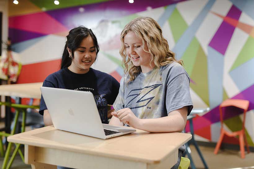 Two UA students complete homework for their undergraduate business degree.