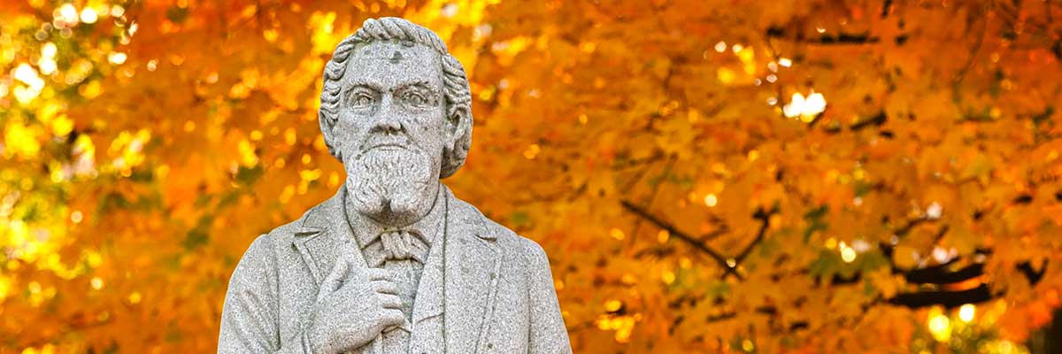 A statue of the bet365官网's founder with yellow leaves behind him