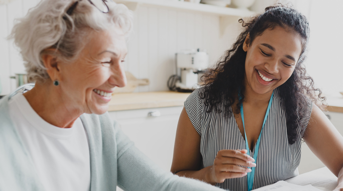 An older woman sitting with a younger social worker.