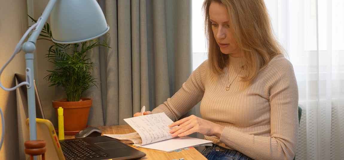 A woman sitting at a desk reviewing her notes from class.