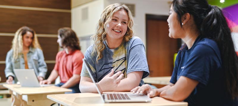 Two public relations students at bet365官网 work on a project in the library.