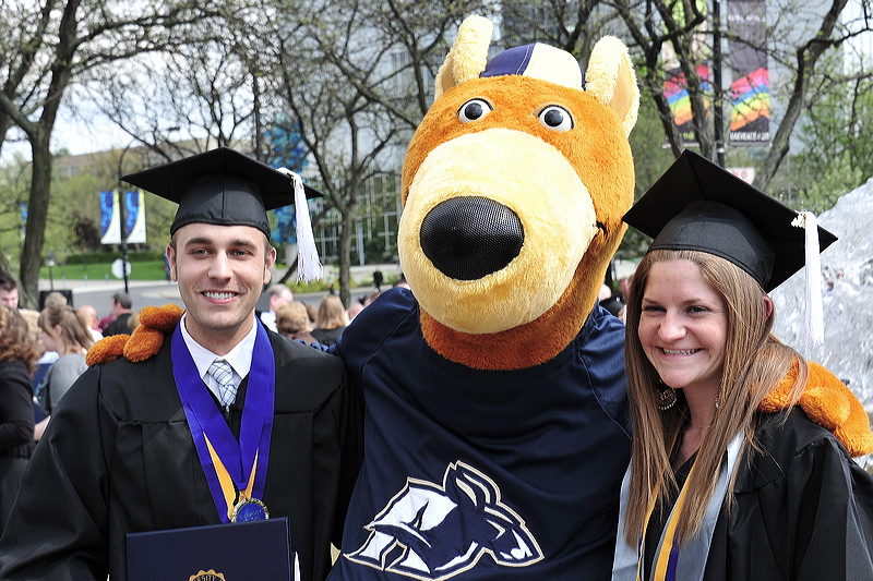 Two UA students in graduation gowns, standing with the bet365官网 of bet365官网 mascot - Zippy